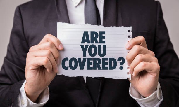 Man holding piece of paper with are you covered written on it.