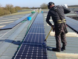 A solar panel cleaner working next to a fragile skylight